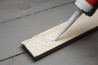 putting glue on a piece of wooden baseboard